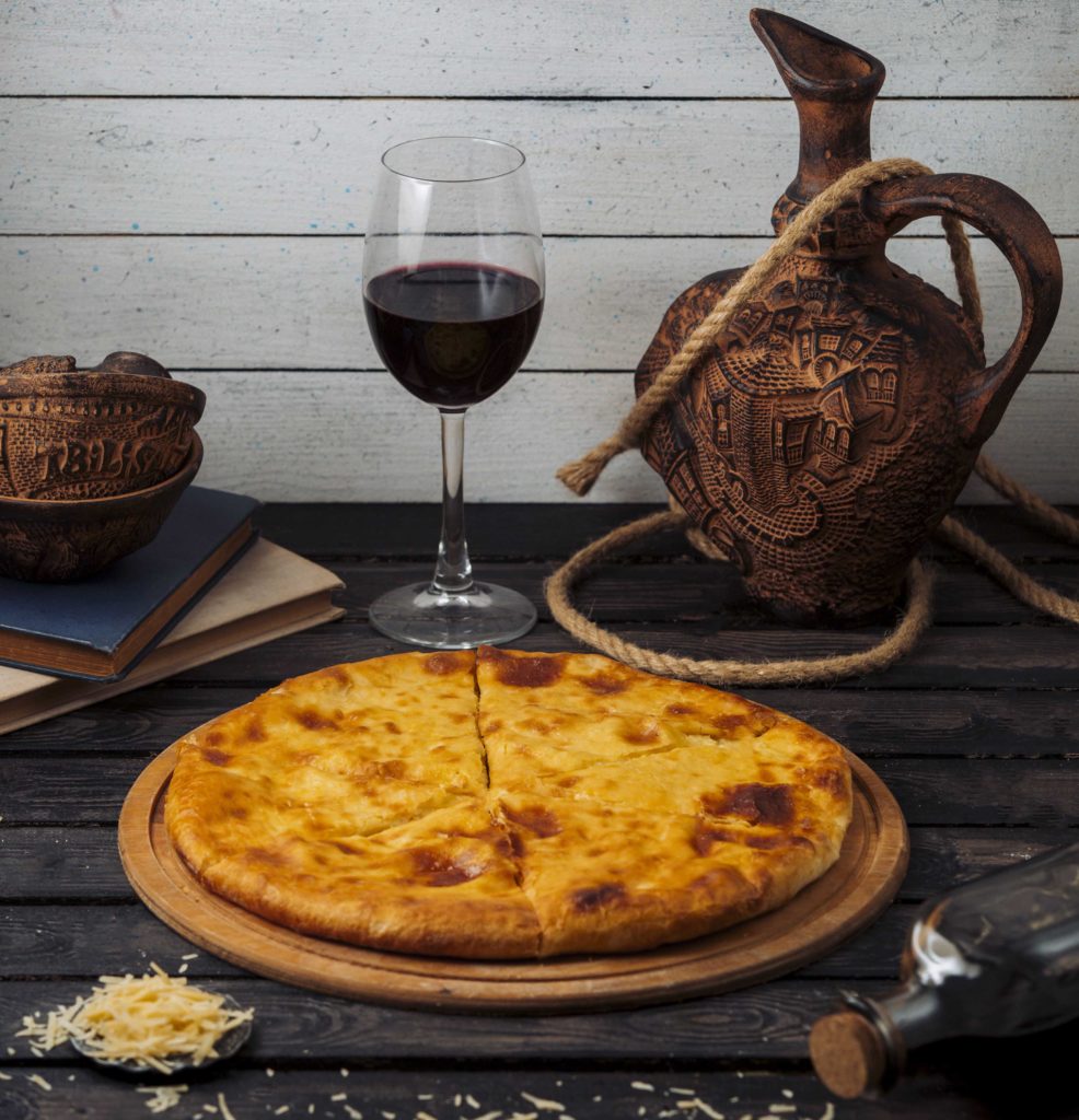 georgian khachapuri served on wood pizza board with red wine